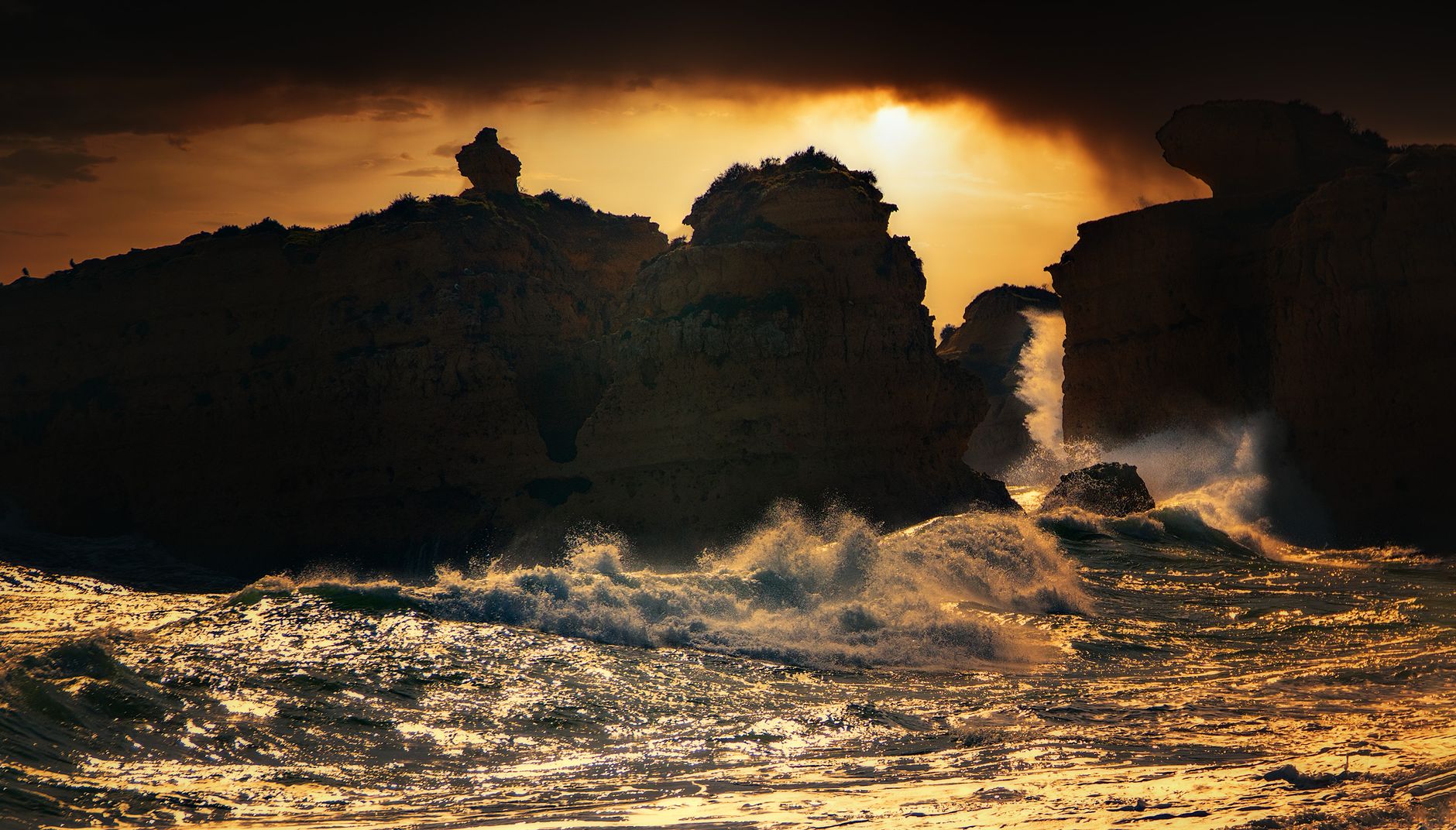 Waves crashing against rocky sea cliffs at sunset